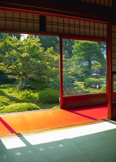 View through traditional Japanese sliding shoji doors with wooden frames and translucent paper panels, opening to a lush green garden with well-maintained trees, bushes, and grass. The tatami mat flooring inside the room appears clean and smooth, with sunlight casting shadows on the floor and warm orange-red step leading outside. The scene emphasizes a serene and tidy living space, highlighting the importance of surface cleaning and maintenance in creating a peaceful home environment, as promoted by Holland Park Cleaner for residential cleaning and deep cleaning services.